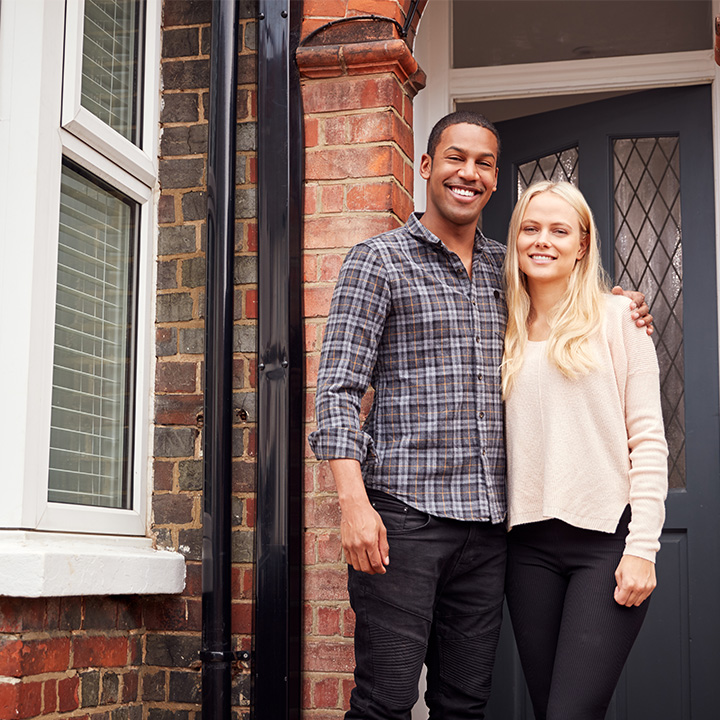 Couple moving home and standing outside new house