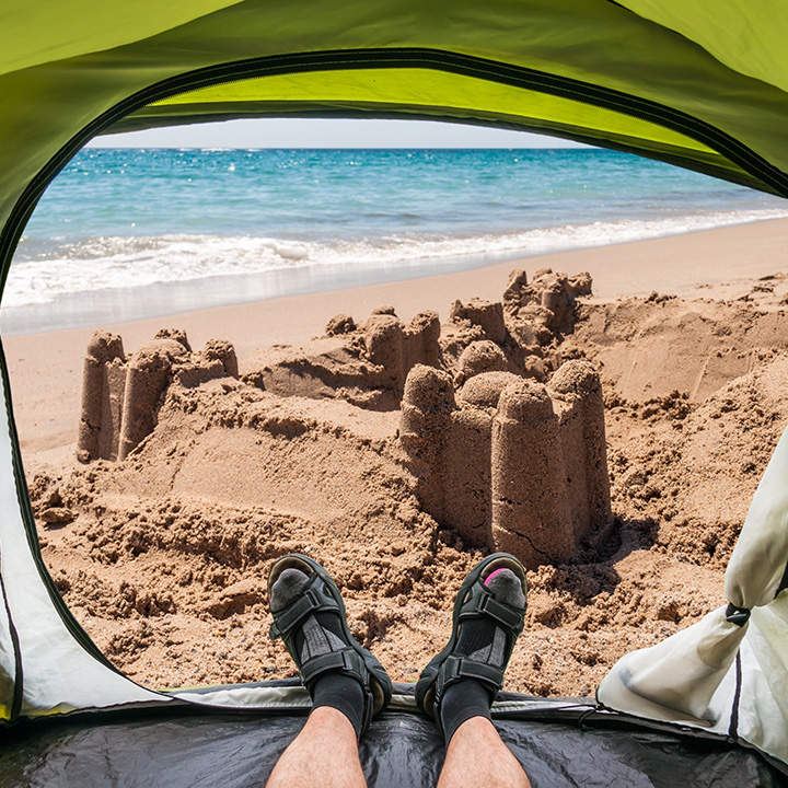 Someone sat in a tent on the beach with their legs sticking out