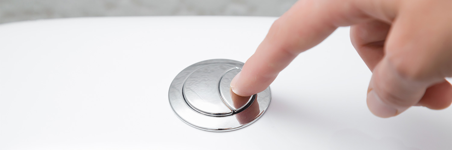 Close up of person pushing a dual flush on a toilet